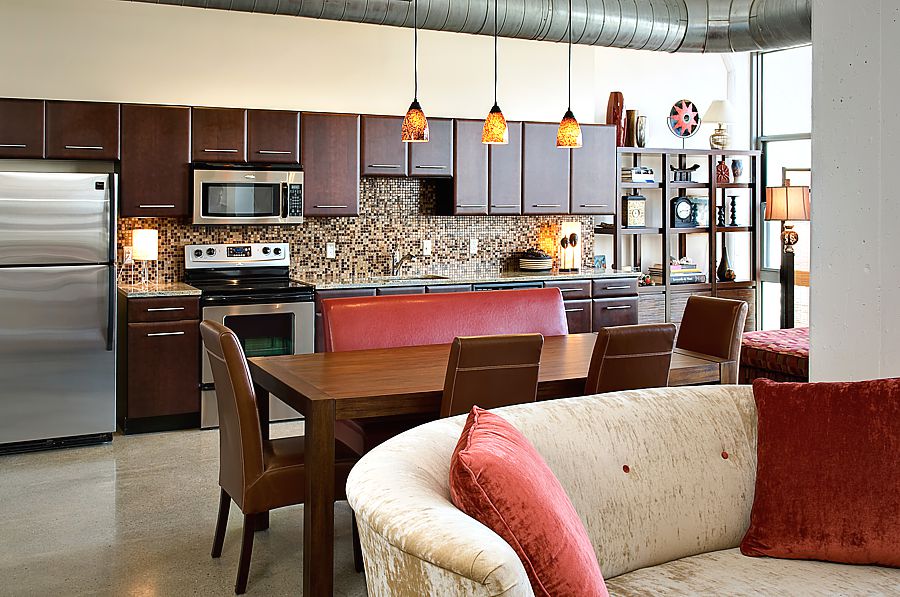 This industrial living room makeover in a loft uses warm colors to work with the cold concrete and ducting that can be part of loft living.